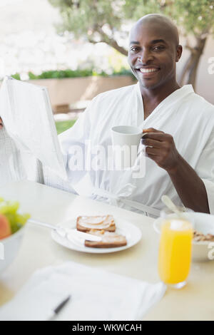 Schöner Mann im Bademantel in das Frühstück im Freien an einem sonnigen Tag Stockfoto