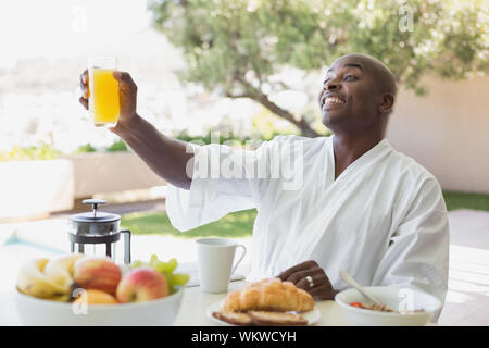 Schöner Mann im Bademantel in das Frühstück im Freien an einem sonnigen Tag Stockfoto