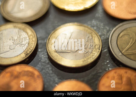 Glänzend 1 Euro Münzen und einige andere um, auf einem Glastisch schließen. Stockfoto