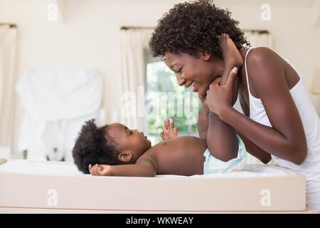 Glückliche Mutter mit Baby Mädchen auf Wickeltisch zu Hause im Schlafzimmer Stockfoto