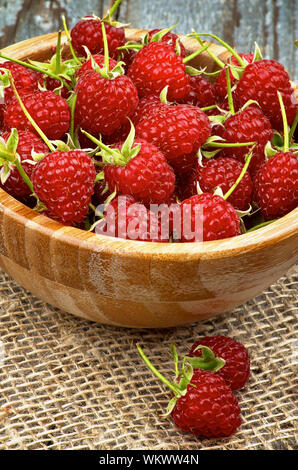 Perfekte Reife Himbeeren mit Stängel in Houten closeup auf Sack und rustikalen Holzmöbeln Hintergrund Stockfoto