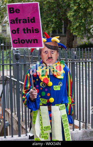 London, Großbritannien. 4. September, 2019. Ein Aktivist gekleidet wie ein Clown das Tragen eines Boris Johnson Maske und halten ein Schild lesen' Angst vor diesem Clown' steht in der Nähe von Parlament in Westminster sein wie das House of Commons Debatten einen Gesetzentwurf, der kein Abkommen Brexit zu verhindern. Credit: Mark Kerrison/Alamy leben Nachrichten Stockfoto