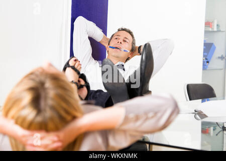 Reifen Geschäftsmann entspannen im Büro, schiefen Füßen auf dem Schreibtisch Stockfoto
