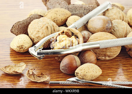 Gemischte Nüsse und einer Mutter Cracker auf einem Holztisch mit Reflexion in Holz. Geringe Tiefenschärfe. Stockfoto