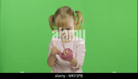 Kind Spaß machen ping Schleim. Kid spielen mit Hand gemacht Spielzeug Schleim. Lustig kind Mädchen. Entspannung und Zufriedenheit. Seltsamerweise zufriedenstellend rosa Schleim für puren Spaß und Stress Relief. Green Screen. Chroma Key Stockfoto