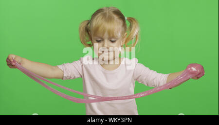 Kind Spaß machen ping Schleim. Kid spielen mit Hand gemacht Spielzeug Schleim. Lustig kind Mädchen. Entspannung und Zufriedenheit. Seltsamerweise zufriedenstellend rosa Schleim für puren Spaß und Stress Relief. Green Screen. Chroma Key Stockfoto