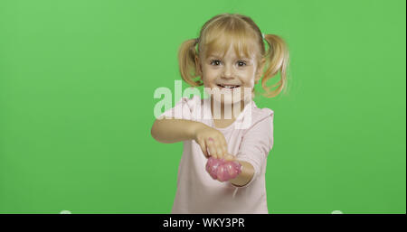 Kind Spaß machen ping Schleim. Kid spielen mit Hand gemacht Spielzeug Schleim. Lustig kind Mädchen. Entspannung und Zufriedenheit. Seltsamerweise zufriedenstellend rosa Schleim für puren Spaß und Stress Relief. Green Screen. Chroma Key Stockfoto