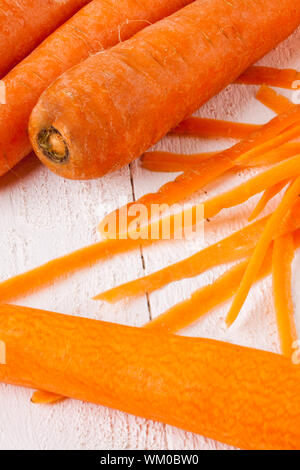 Frische geschälte Karotten in Scheiben geschnitten in dünne Stäbe für Karotten Julienne mit einem Cutter Metall Küche auf weißem Hintergrund Stockfoto