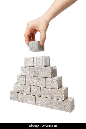 Menschen bauen Pyramide aus kleinen Blöcken von Granitfelsen. Stockfoto