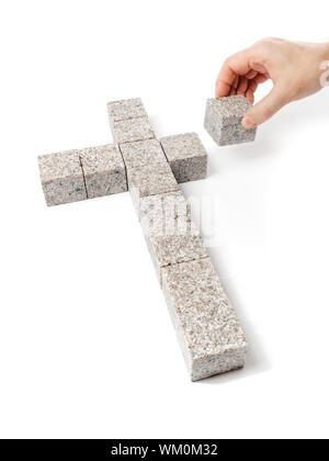 Menschen bauen ein christliches Kreuz machte der kleine Blöcke von Granitfelsen. Stockfoto