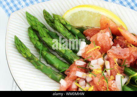 Frisch geernteter Spargel gedünstet und mit Tomaten und Himbeer-Vinaigrette serviert. Stockfoto