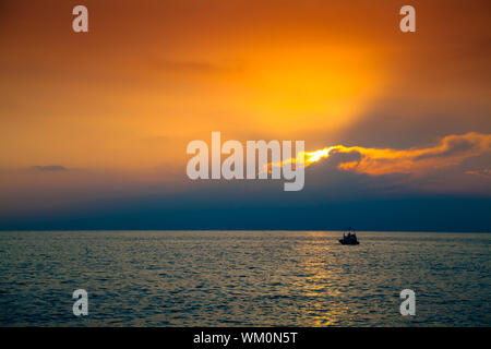 Einsame Boot im Meer an der wunderschönen Sonnenuntergang Stockfoto
