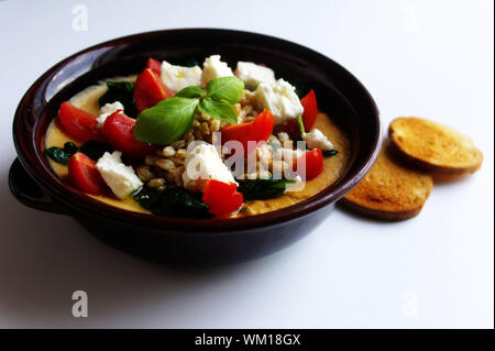 Gesunde Mahlzeiten: Gerste Suppe in einer Schüssel mit Kichererbsen, Spinat, Schafskäse, Tomaten, Basilikum und geröstetem Brot. Stockfoto