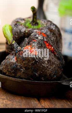 drei frische Paprika Charcol verbrannten über alten Holztisch auf eine skillett Stockfoto