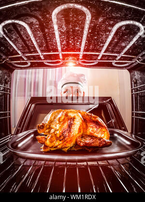 Chefkoch gebratenes Huhn in den Ofen, Blick aus dem Inneren des Ofens. Kochen in den Ofen. Stockfoto