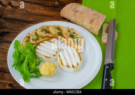 Gegrillter Camembert mit Baguette und Senf mit Rucola-Salat Stockfoto