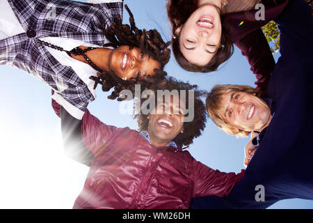 Eine glückliche Gruppe umarmen von Freunden - mit Sonneneruption von links unten Stockfoto