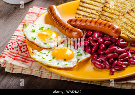 Englisches Frühstück - Knoblauch-Toast, Spiegelei, Bohnen und Bohnenkraut Wurst Stockfoto