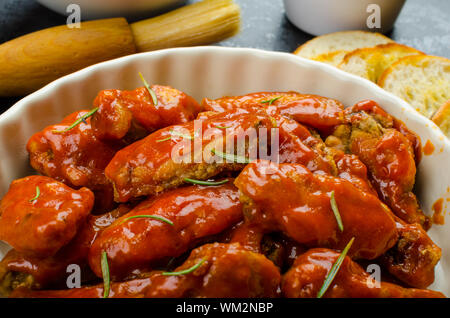 Heißen Hähnchenflügel mit würziger Habanero Sauce und gemischtem Salat mit Cherry-Tomaten, gegrilltes Baguette mit Olivenöl Stockfoto