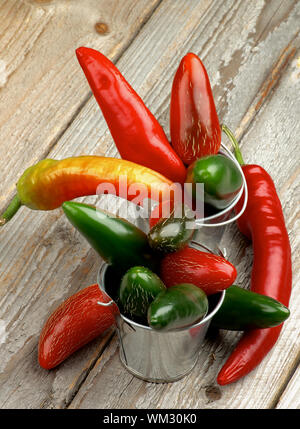Die Anordnung der Roten und Grünen Habanero, Jalapeno Chili Peppers in Dose Eimer auf rustikalen Holzmöbeln Hintergrund Stockfoto