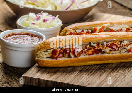 Schweinesandwich, lange gebackenes Schweinefleisch, in frischem Baguette mit frischem Salat und heiße Sause gezogen gezogen Stockfoto