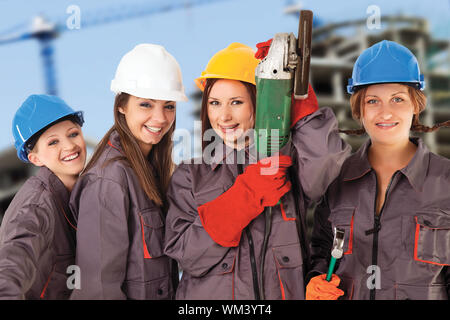 Vier yung Frauen Tragen von Kleidung und Helme mit Arbeit weg vor einem Bau Hintergrund isoliert. Stockfoto
