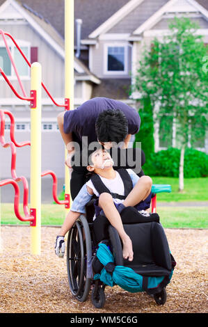 Behinderte Junge im Rollstuhl mit Big Brother im Park Stockfoto