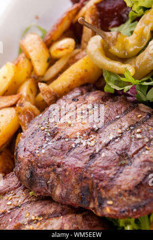 Gesunde platter gemischter Aufschnitt einschließlich gegrilltes Steak, knusprig panierte Hähnchen und Rindfleisch auf einem Bett von frischem grünem Salat serviert mit Französischen Stockfoto