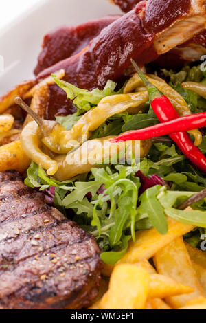 Gesunde platter gemischter Aufschnitt einschließlich gegrilltes Steak, knusprig panierte Hähnchen und Rindfleisch auf einem Bett von frischem grünem Salat serviert mit Französischen Stockfoto