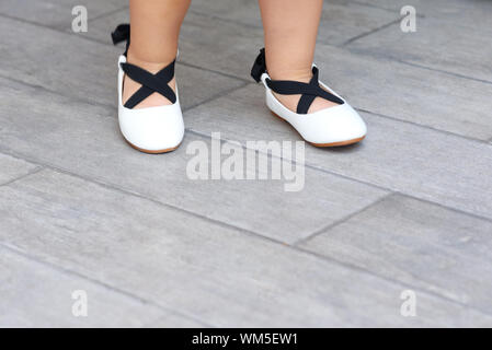 Schließen Sie die niedlichen kleinen Mädchen Beine in neuen Wohnungen. Baby Mädchen in ein Schuhgeschäft. Kleinkind Kind spielen und versuchen, Ballerina Schuhe in einem Supermarkt. Stockfoto