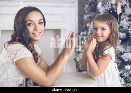 Mutter mit Kind Tochter in schöne Mode flower dress Feiern in der Nähe von Weihnachten Baum angezogen Stockfoto