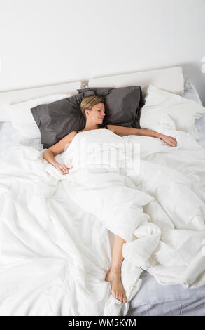 Frau schlafen in einem weißen Schlafzimmer Umgebung von hohen Winkel anzeigen Stockfoto