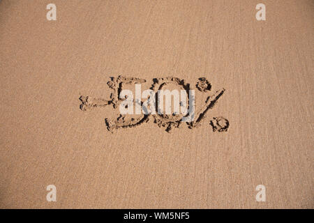 50 Prozent Rabatt im Erde Text geschrieben am braunen Sandboden Ebbe Strand Meeresküste in Spanien Europa Stockfoto