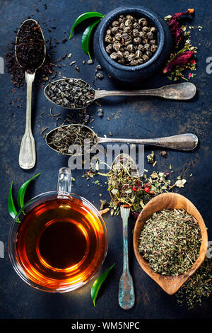 Tee-Komposition mit verschiedenen Arten von Tee und alte Löffel auf dunklem Hintergrund Stockfoto