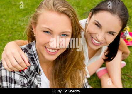 Teens beste Freunde sitzen auf dem Rasen Lächeln auf den Lippen und eine gute Zeit Stockfoto