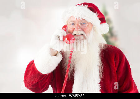 Santa claus am Telefon gegen blurry Christbaum im Zimmer Stockfoto