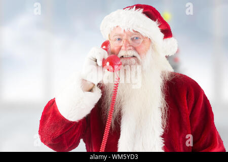 Santa claus am Telefon gegen blurry Christbaum im Zimmer Stockfoto
