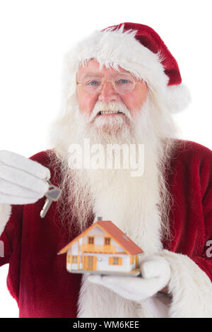 Santa Hände der Schlüssel zu einem winzigen Haus auf weißem Hintergrund Stockfoto