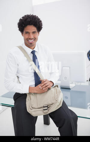 Lächelnd Geschäftsmann mit Schultertasche in seinem Büro Stockfoto