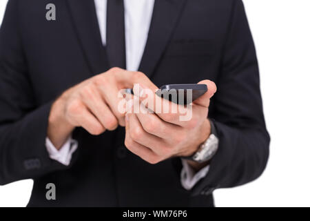 Den mittleren Abschnitt der ein Geschäftsmann mit Smartphone auf weißem Hintergrund Stockfoto