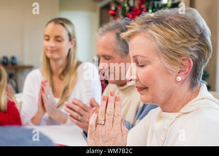 Erweiterte Familie sagen Gnade vor Weihnachten Abendessen zu Hause im Speisesaal Stockfoto