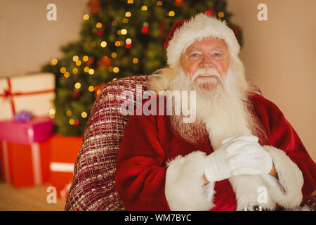 Smiling Santa Claus entspannen auf dem Sessel zu Hause im Wohnzimmer Stockfoto