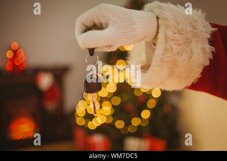 Hand der Weihnachtsmann holding Auto zu Hause im Wohnzimmer Schlüssel Stockfoto