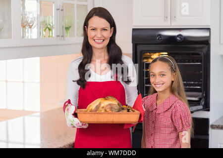 Überrascht Mutter und Tochter posiert mit gebratenem Truthahn zu Hause in der Küche Stockfoto