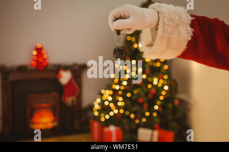 Hand der Santa mit dem Schlüssel zu Hause im Wohnzimmer Stockfoto
