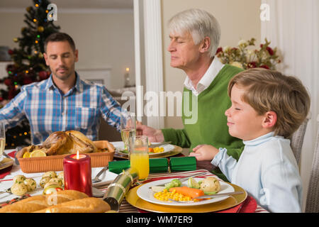 Erweiterte Familie sagen Gnade vor Weihnachten Abendessen zu Hause im Wohnzimmer Stockfoto