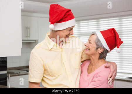 Senior Paar tragen Nikolausmützen zu Hause in der Küche Stockfoto