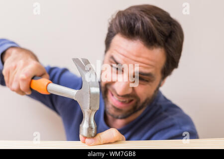 Legerer mann Hämmern seinen Finger durch Unfall zu Hause im Wohnzimmer Stockfoto