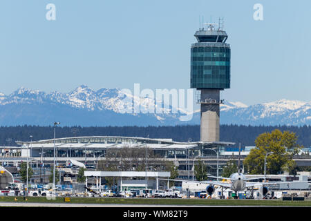 Air Traffic Control Tower in Vancouver Intl. Flughafen (YVR) mit schneebedeckten Bergen im Hintergrund gesehen. Stockfoto