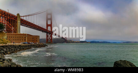 Die berühmte Golden Gate Bridge an einem bewölkten Sommertag mit niedrig hängenden Nebel rollen in San Francisco, Kalifornien Stockfoto